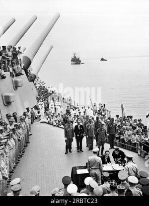 Tokio, Japan: 1. September 1945 General Douglas MacArthur (zurück in die Kamera) sieht dem japanischen Außenminister Mamoru Shigemitsu zu, wie er an Bord der USS Missouri in der Bucht von Tokio das Kapitulationsdokument unterschreibt. Stockfoto