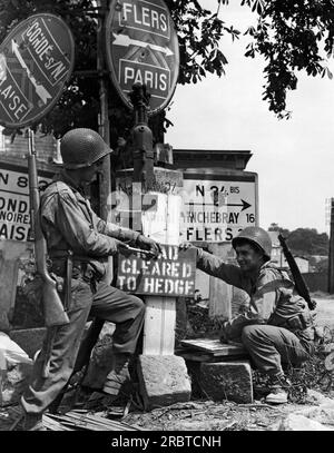 Vire, Paris, Frankreich, 11. August 1944 Charles Lynch, Hollsopple, PA, und Louis Motto, Cleveland, Ohio, US-Ingenieure schnappen sich ein Schild, das anzeigt, dass der Weg vor uns von Minen geräumt wurde. Stockfoto
