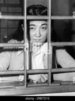 Yokohama, Japan, 28. Oktober 1945 Iva Toguri, bekannt als „Tokyo Rose“ der japanischen Propaganda „Zero Hour“-Sendungen, die während des Krieges auf US-Truppen im Pazifik gebeamt wurden, während sie durch die Gitter ihrer Zelle blickt. Sie wurde 1916 in Los Angeles geboren und wartet auf den Prozess wegen Hochverrats gegen die Vereinigten Staaten. Stockfoto