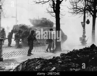 Frankfurt, Deutschland, 7. April 1945 bewaffnete Infanteristen der Dritten Armee der USA decken sich hinter einem Panzerfeuer in die Industriestadt Frankfurt. Rauch und Staub aus den explodierenden Muscheln sind ein Schutzschild für die Yankees, die darauf warten, die Stadt zu stürmen. Stockfoto