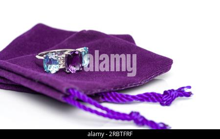 Amethyst mit blauem Topas und weißem Saphir-Juwel oder Edelsteinen Ring auf violettem Samtbeutel. Sammlung von Accessoires für natürliche Edelsteine. Studioaufnahme Stockfoto