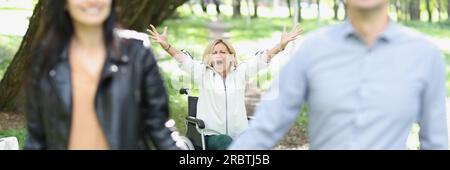 Glückliches Paar vergaß behinderte Frau im Rollstuhl im Freien. Stockfoto