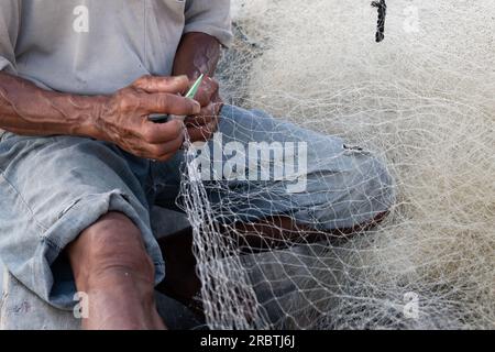 Der Mann repariert ein Fischernetz auf einem Boot in einem Dorf in Indonesien Stockfoto