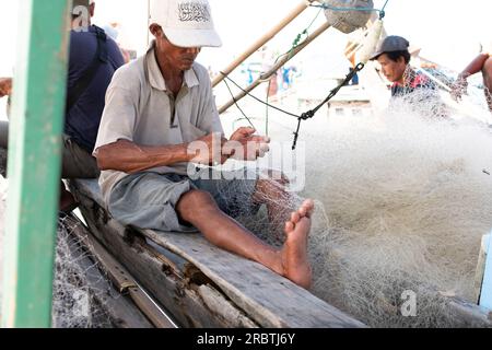 Lampung, Indonesien, Juni 18 2023: Der Fischer repariert das Fischernetz auf dem Boot im Dorf Indonesien Stockfoto