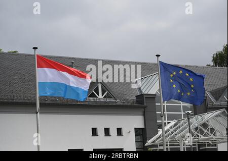 Marnach, Luxemburg. 08. Juli 2023. Die Flagge der EU, der Europäischen Union, der Europäischen Union - Sie zeigt einen Kreis von zwölf goldenen Sternen auf blauem Hintergrund und die Flagge Luxemburgs (links), die im Wind winkt. Die heutige luxemburgische Flagge besteht aus drei horizontalen Streifen in Rot, Weiß und Himmelblau. Kredit: Horst Galuschka/dpa/Alamy Live News Stockfoto