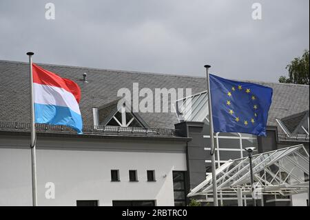 Marnach, Luxemburg. 08. Juli 2023. Die Flagge der EU, der Europäischen Union, der Europäischen Union - Sie zeigt einen Kreis von zwölf goldenen Sternen auf blauem Hintergrund und die Flagge Luxemburgs (links), die im Wind winkt. Die heutige luxemburgische Flagge besteht aus drei horizontalen Streifen in Rot, Weiß und Himmelblau. Kredit: Horst Galuschka/dpa/Alamy Live News Stockfoto
