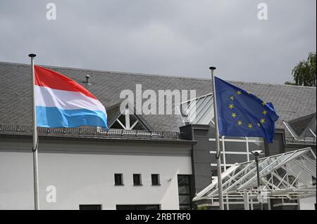 Marnach, Luxemburg. 08. Juli 2023. Die Flagge der EU, der Europäischen Union, der Europäischen Union - Sie zeigt einen Kreis von zwölf goldenen Sternen auf blauem Hintergrund und die Flagge Luxemburgs (links), die im Wind winkt. Die heutige luxemburgische Flagge besteht aus drei horizontalen Streifen in Rot, Weiß und Himmelblau. Kredit: Horst Galuschka/dpa/Alamy Live News Stockfoto