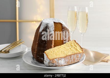 Köstlicher Pandoro-Kuchen mit Puderzucker und Gläsern Sekt auf einem weißen Holztisch. Traditionelles italienisches Gebäck Stockfoto