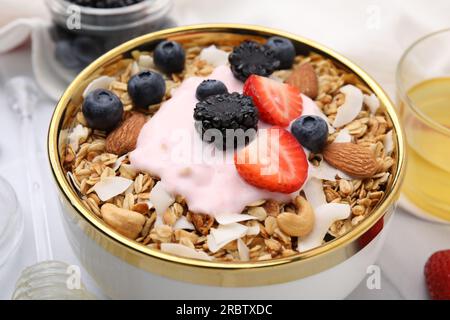 Leckeres Müsli, Joghurt und frische Beeren in der Schüssel auf dem Tisch, Nahaufnahme. Gesundes Frühstück Stockfoto