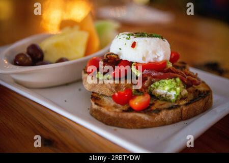 Avocado-Toast mit Eiern und Obst als Beilage Stockfoto