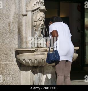 Person tanken Sie am Brunnen auf dem Loggia-Platz in Brescia mit Wasser auf Stockfoto