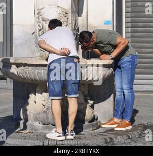 Person tanken Sie am Brunnen auf dem Loggia-Platz in Brescia mit Wasser auf Stockfoto