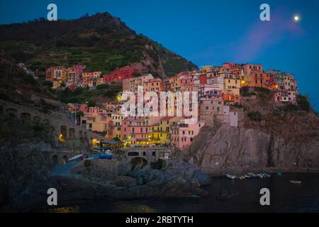 Cinque Terre, Italien - Nachtsicht auf die farbenfrohen Pastellhäuser in Manarola, einem Küstendorf an der zerklüfteten italienischen Riviera Küste. Sommerurlaub. Stockfoto