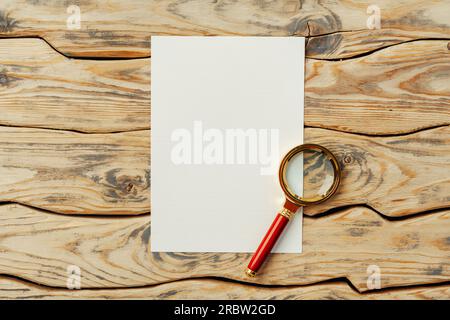 Vergrößerungsglas auf altem Papier auf dunkelbraunem Holz-Backgorund Stockfoto