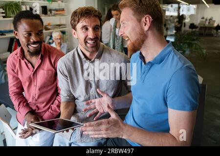 Lächelnd treffen sich verschiedene Kollegen in einem Brainstorming in der Vorstandsetage, um gemeinsam Finanzstatistiken zu diskutieren Stockfoto