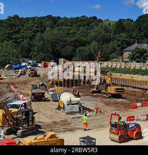 Blick von der Spitze des Toddbrook-Staudamms hinunter, während ein Bagger die Erde ausgräbt, um den Bau der neuen Fallbucht mit Reparaturen am Staudamm vorzubereiten Stockfoto