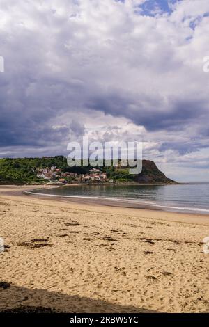 Runswick Bay Beach bei Ebbe. Blick vom Strand auf den Sand und das Dorf, eingebettet unter den Klippen. Bei Ebbe im Sommer geschossen. Runswick Bay i Stockfoto