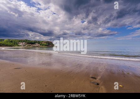 Der Sandstrand von Runswick Bay ist bei Ebbe freigelegt. Dieses Foto wurde auf halbem Weg um die Bucht mit Blick auf das Dorf gemacht. Stockfoto