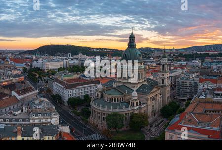 Unvergleichlicher Blick auf die Skyline des berühmten St. Stepehens Basilika in der Innenstadt von Budapest. Das Stadtbild aus der Vogelperspektive. Spektakulärer Sonnenuntergang über den Hügeln von Buda. Stockfoto