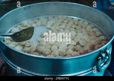 Traditionelles, sehr beliebtes nepalesisches Essen. Nepalesische gedämpfte Teigtaschen momo kochen auf der Party in einem großen Dampftopf für eine große Anzahl von Personen. Nahaufnahme im Stockfoto