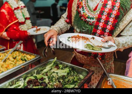 Hochzeitspaar, das Essen vom Buffet bei der Hochzeit nimmt Stockfoto