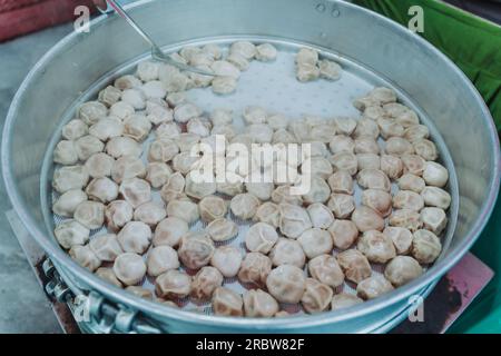 Traditionelles, sehr beliebtes nepalesisches Essen. Nepalesische gedämpfte Teigtaschen momo kochen auf der Party in einem großen Dampftopf für eine große Anzahl von Personen. Nahaufnahme im Stockfoto