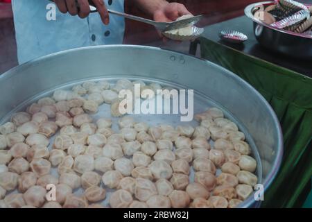 Traditionelles, sehr beliebtes nepalesisches Essen. Nepalesische gedämpfte Teigtaschen, momo, Kochen und Servieren auf der Party. Nahaufnahme. Stockfoto