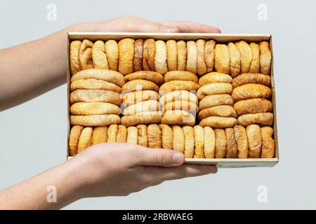 Verpackte Feigen in den Händen. Box mit getrockneten Früchten in den Händen.Concept gesunde, biologische, vegane Lebensmittel. Nahaufnahme. Stockfoto