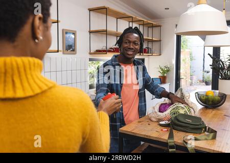Glückliches afroamerikanisches Paar, das Lebensmittel in der Küche auspackt Stockfoto