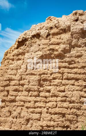 Die gebogene Oberseite einer Lehmwand zeigt gestapelte Lehmziegel und Mörtelfugen vor einem blauen Himmel am Fort Selden State Monument in New Mexico. Stockfoto