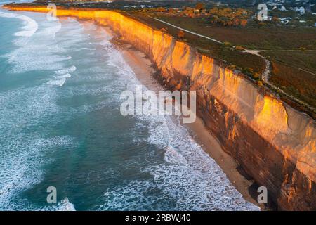 Aus der Vogelperspektive sehen Sie Wellen, die am Fuße der hohen Meeresklippen bei Anglesea auf der Great Ocean Road in Victoria, Australien, krachen Stockfoto