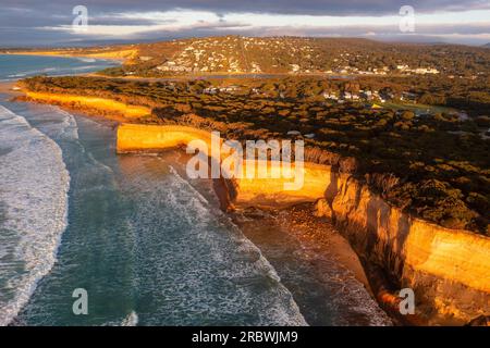 Aus der Vogelperspektive sehen Sie Wellen, die am Fuße der hohen Meeresklippen bei Anglesea auf der Great Ocean Road in Victoria, Australien, krachen Stockfoto