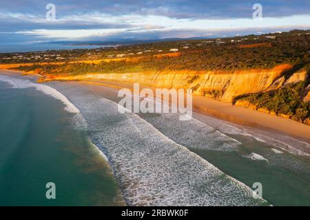 Aus der Vogelperspektive sehen Sie Wellen, die am Fuße der hohen Meeresklippen bei Anglesea auf der Great Ocean Road in Victoria, Australien, krachen Stockfoto