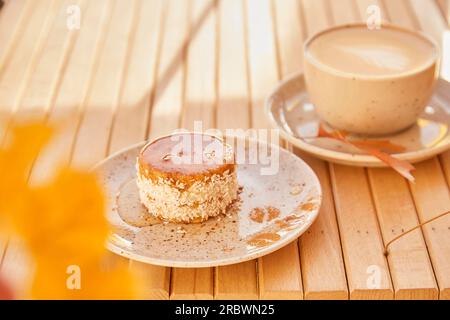 Gesunde Karotten, kein Backen und kein Zucker, leichtes Dessert mit Agavesirup. Glutenfreier Kuchen mit einer Tasse Kaffee draußen im Schatten. Stockfoto