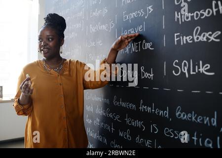 Afroamerikanischer Lehrer, der auf die Tafel zeigt und den Schülern LEKTION ERTEILT Stockfoto