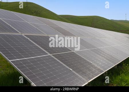 Nahaufnahme von Sonnenkollektoren vor dem Hintergrund grüner Berge an einem Sommertag. Stockfoto