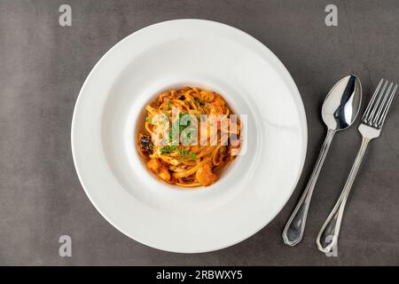 Garnelen-Spaghetti auf weißer Porzellanplatte auf schwarzem Steintisch Stockfoto