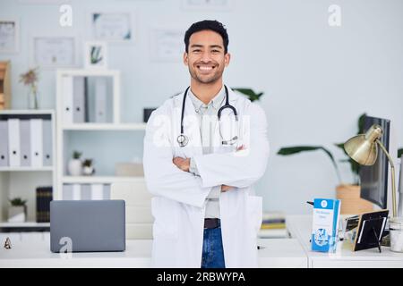Glücklicher asiatischer Mann, Arzt und Arme gekreuzt im Vertrauen des Gesundheitsberaters in der Praxis. Portrait von selbstbewussten und männlichen Person oder medizinisch Stockfoto
