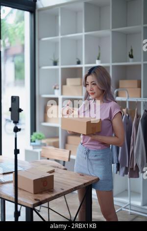 Schöne asiatische Frau, Blogger, Blog, Modebekleidung präsentieren, Live-Video, Soziale Medien, Aufnahme, Online-Verkauf über Digitalkameras, kmu oder kleine unternehmen Stockfoto