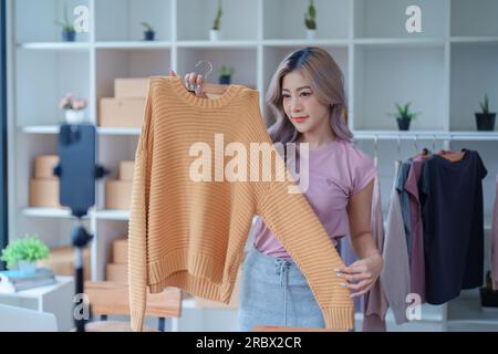 Schöne asiatische Frau, Blogger, Blog, Modebekleidung präsentieren, Live-Video, Soziale Medien, Aufnahme, Online-Verkauf über Digitalkameras, kmu oder kleine unternehmen Stockfoto