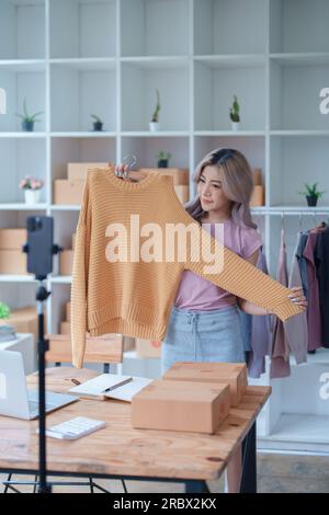 Schöne asiatische Frau, Blogger, Blog, Modebekleidung präsentieren, Live-Video, Soziale Medien, Aufnahme, Online-Verkauf über Digitalkameras, kmu oder kleine unternehmen Stockfoto
