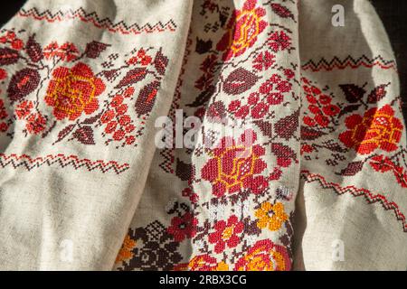 Besticktes Hemd mit ukrainischer Kleidung. Rot-orangefarbene Fäden als Hintergrund. Wyschywanka ist ein Symbol der Ukraine. Stickerei mit Kreuzstickerei. Nationales ukrainisches Stich. Traditionelles Bekleidungssymbol. Stockfoto