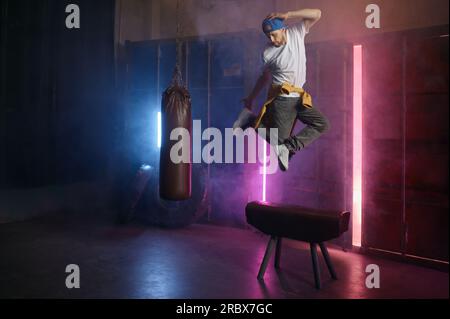 Ein junger erwachsener B-Boy Breakdancer, der über den Hintergrund des Loft-Fitnessstudios springt Stockfoto
