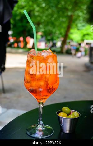 Der Kellner bereitete den Aperol Sprits Sommercocktail mit Aperol, Prosecco, Eiswürfeln, Tonic Wasser und Orange in Weinglas zu, bereit zum Trinken auf einem sonnigen Terr Stockfoto