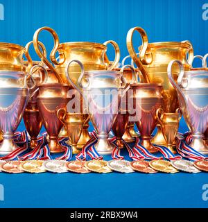 Ausstellung von Gold-, Silber- und Bronzemedaillen und Trophäen mit farbenfrohen Bändern, elegant auf einem blauen Tuch angeordnet. Perfekt für Präsentationen, Ceremo Stockfoto