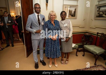 Queen Camilla mit den Gästen Ashley Hickson-Lovence und Daniella Koranteng bei einem Empfang im Clarence House, London, um den 15. Jahrestag der Wohltätigkeitsorganisation „The First Story“ zu feiern. Bilddatum: Dienstag, 11. Juli 2023. Stockfoto