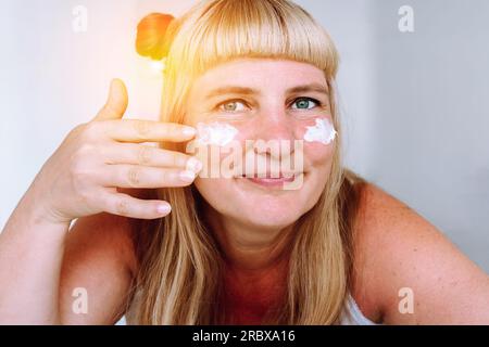 Porträt attraktive blonde Frau mittleren Alters mit kosmetischer Creme Stockfoto
