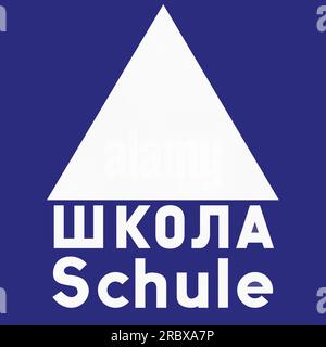 Altes Design (1956) eines deutschen Verkehrsschildes, um auf Grund einer nahe gelegenen Schule Vorsicht zu walten. Beide Wörter bedeuten Schule, auf Deutsch und Russisch. Stockfoto