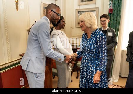 Queen Camilla begrüßt den Gast Ashley Hickson-Lovence bei einem Empfang im Clarence House, London, um den 15. Jahrestag der Wohltätigkeitsorganisation „The First Story“ zu feiern. Bilddatum: Dienstag, 11. Juli 2023. Stockfoto