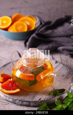Detox-Tee mit Orange und Minze in einer transparenten Teekanne Stockfoto